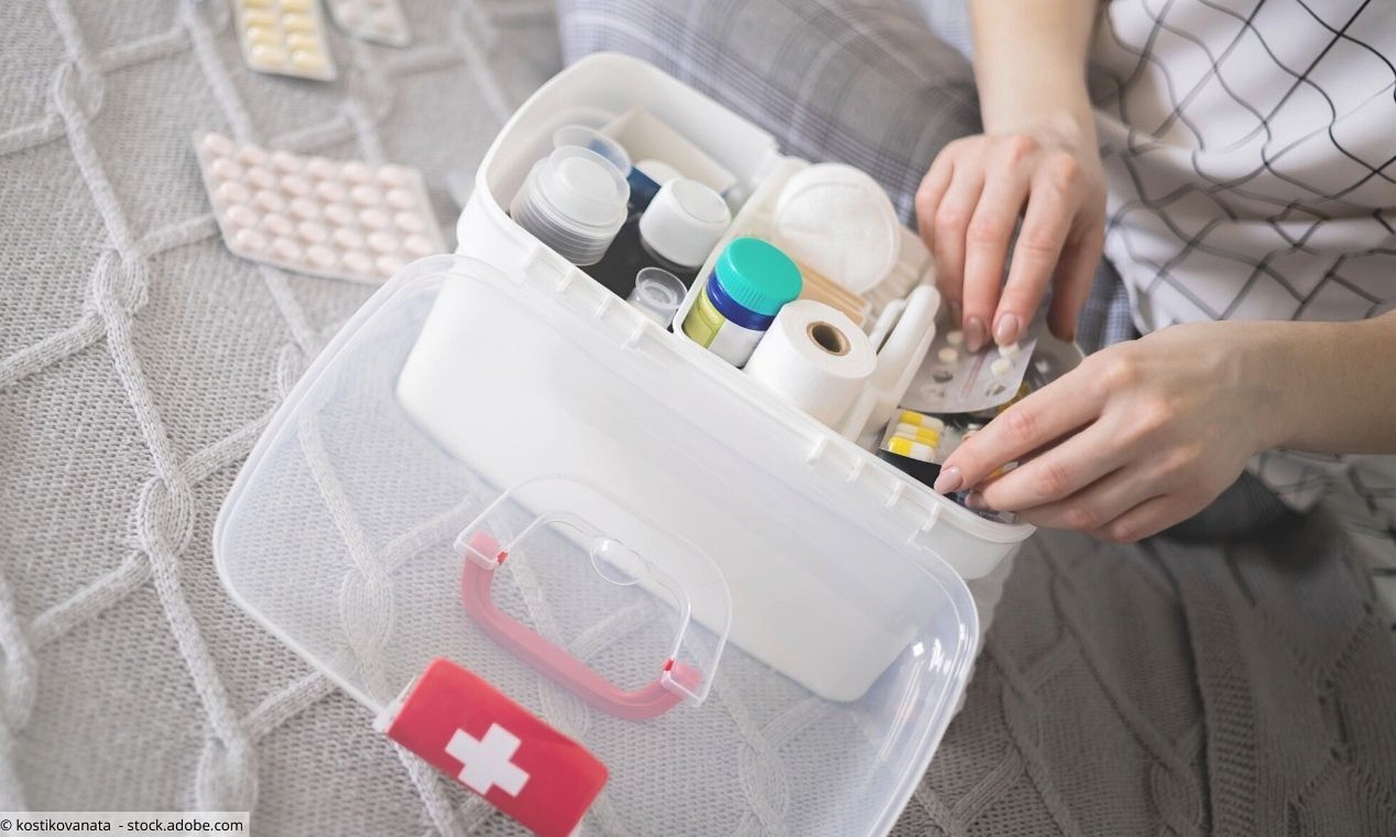 Haltbarkeit, Aufbewahrung und Entsorgung von Medikamenten Frau sortiert Tabletten, Salben, Verbandszeug in Erste-Hilfe-Box