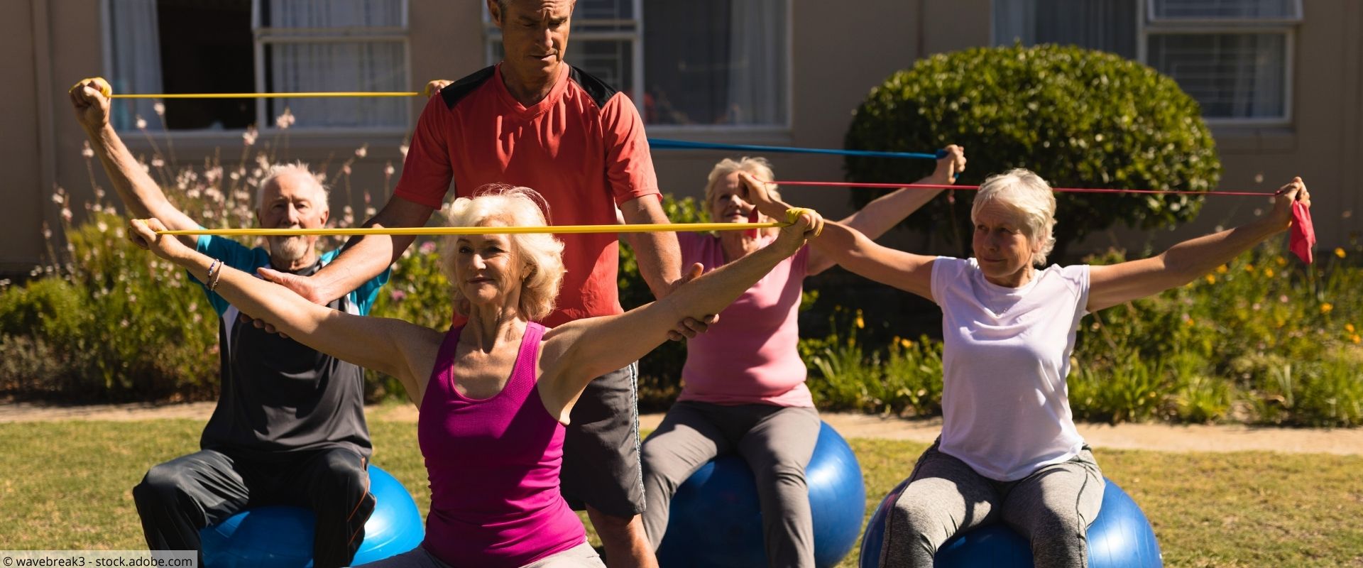 Seniorengruppe auf Gymnastikbällen mit Trainer bei Sportübungen